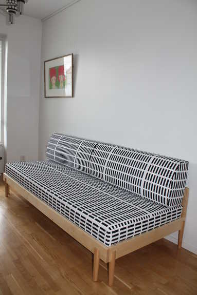 Skandinaaviseen, pelkistettyyn tyyliin muotoiltu koivupuinen vuodesohva design-kankaalla.