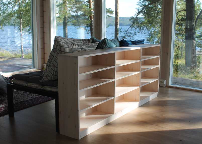 Modernin kesäasunnon kirjahylly on sävytetty seinien mukaan. Hylly toimii samalla selkänojana sohvalle.